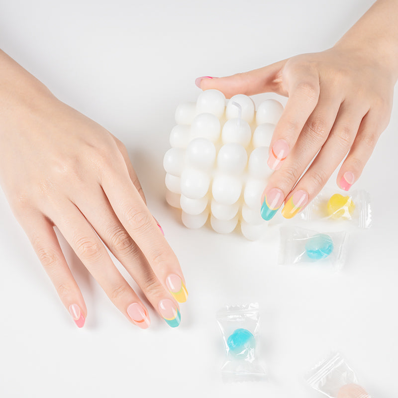Playful rainbow French tip nails on hands, created with a DIY semi-cured gel sticker kit for a colorful, modern twist on a classic manicure.